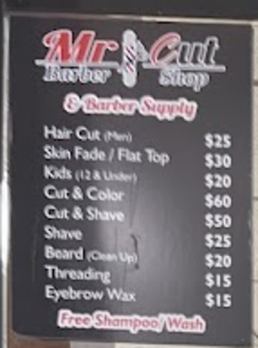 The Mr Cut price board on the shop wall: hair cut $25, skin fade or flat top $30, kids $20, cut and color $60, cut and shave $50, shave $25, beard clean up $20, threading $15, eyebrow wax $15, free shampoo and wash